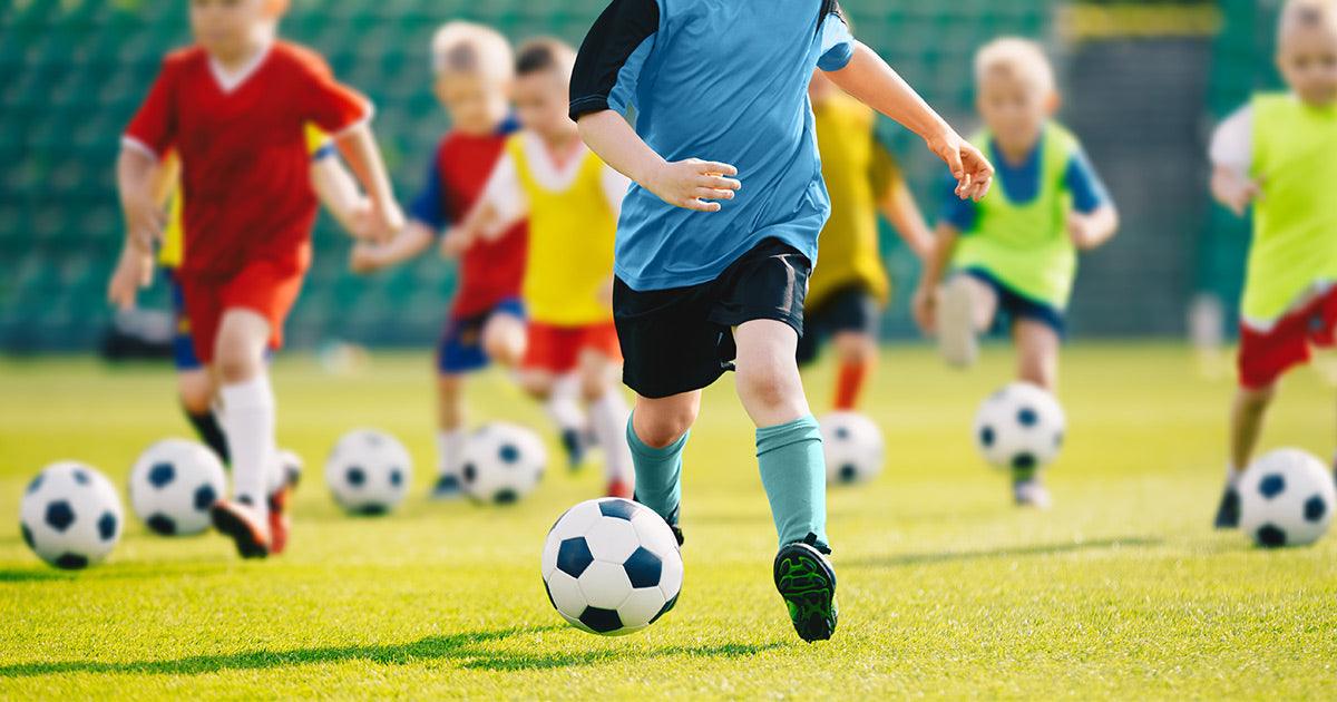 Kids playing soccer on a field representing active children at risk of heel pain and Sever’s disease