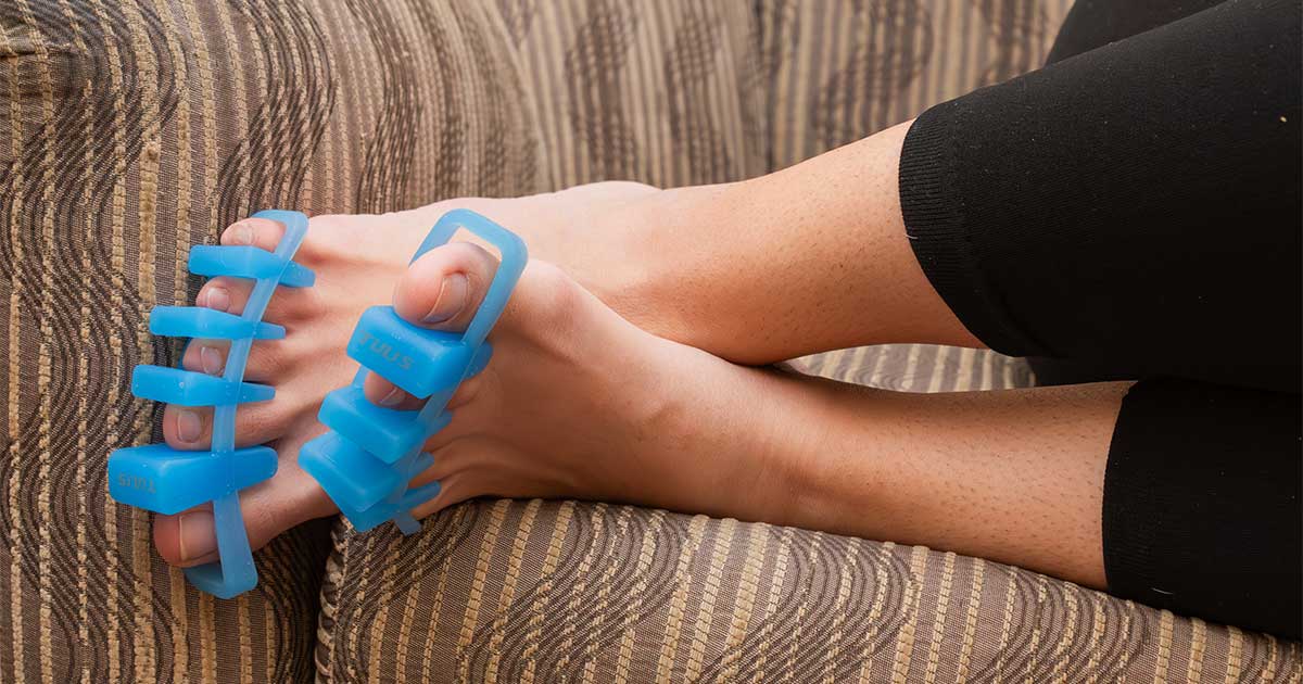 lady using Tuli's Soft Moves Adjustable Toe Separators while on couch.