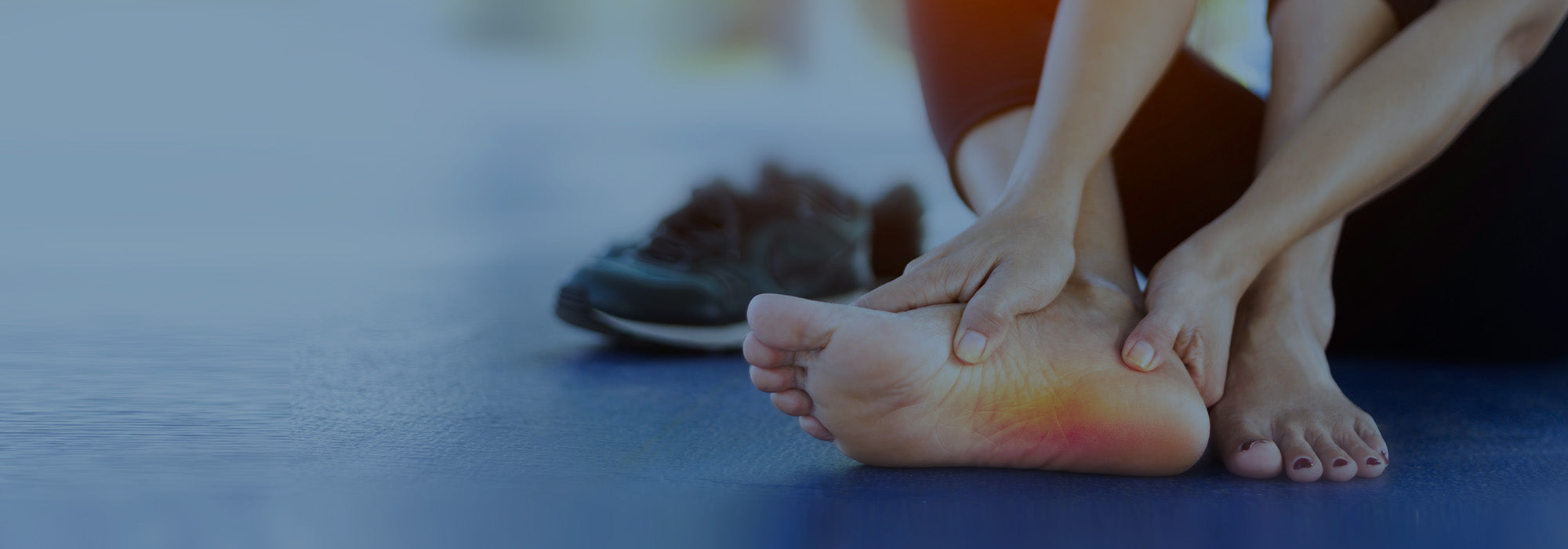 Person holding the bottom of the foot with highlighted heel area indicating foot pain.