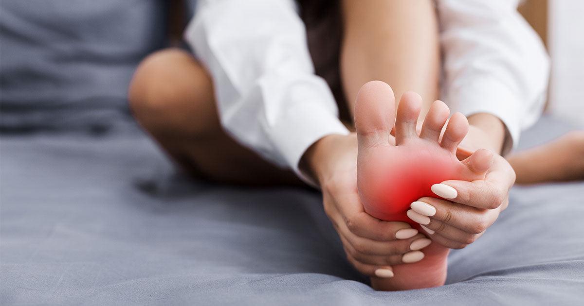 Woman massaging her foot on bed