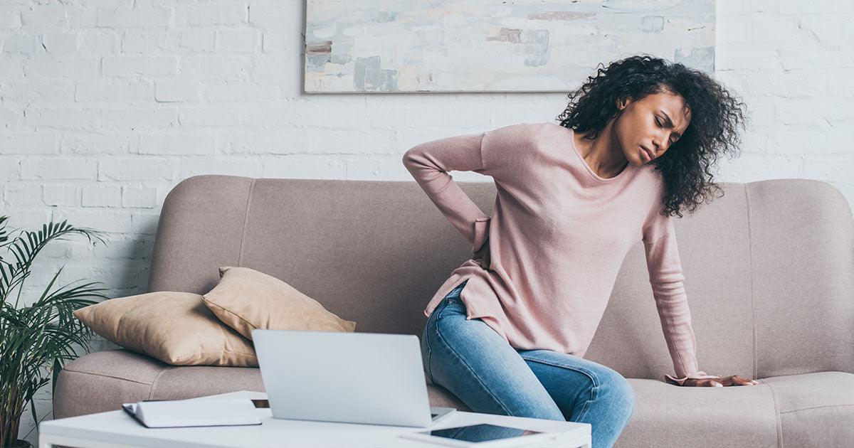 Woman with back pain sitting on couch