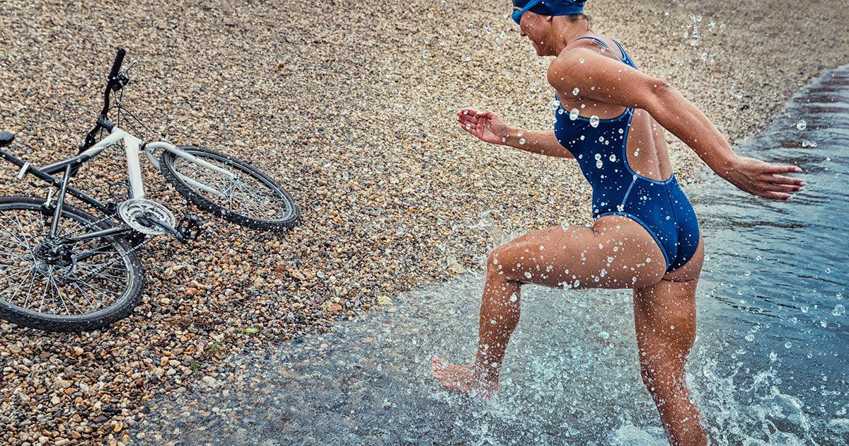 Triathlete running out of the water to bike