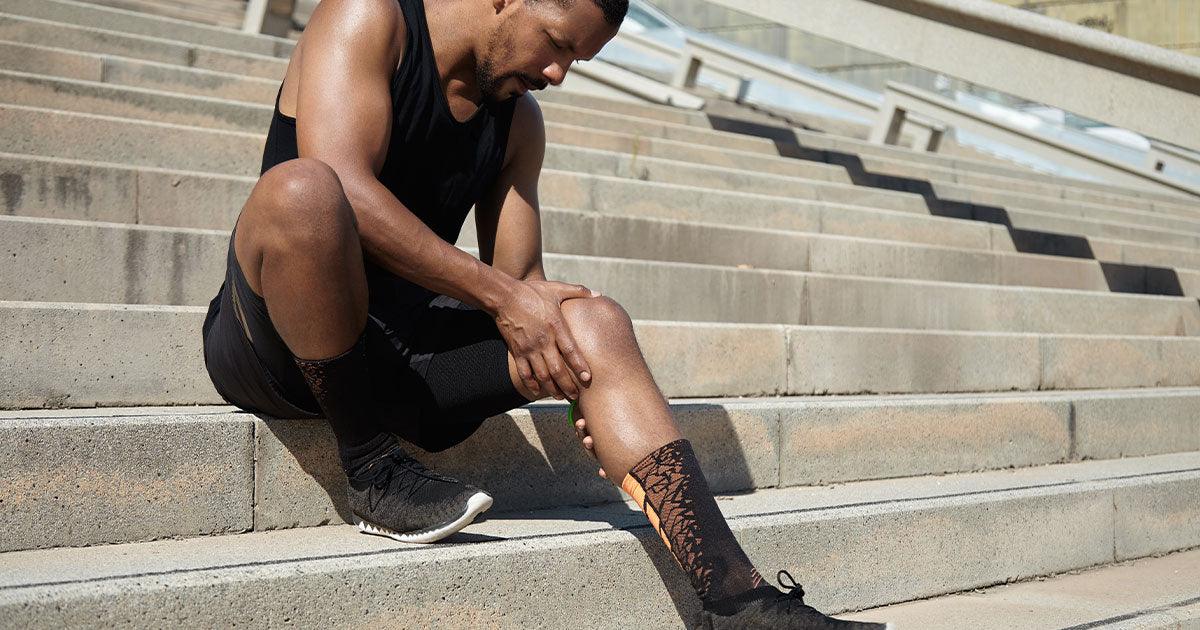 Male jogger sitting massaging calf 