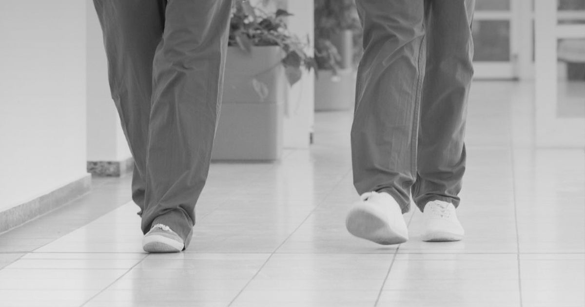 Two people walking indoors, representing healthy foot movement and mobility.