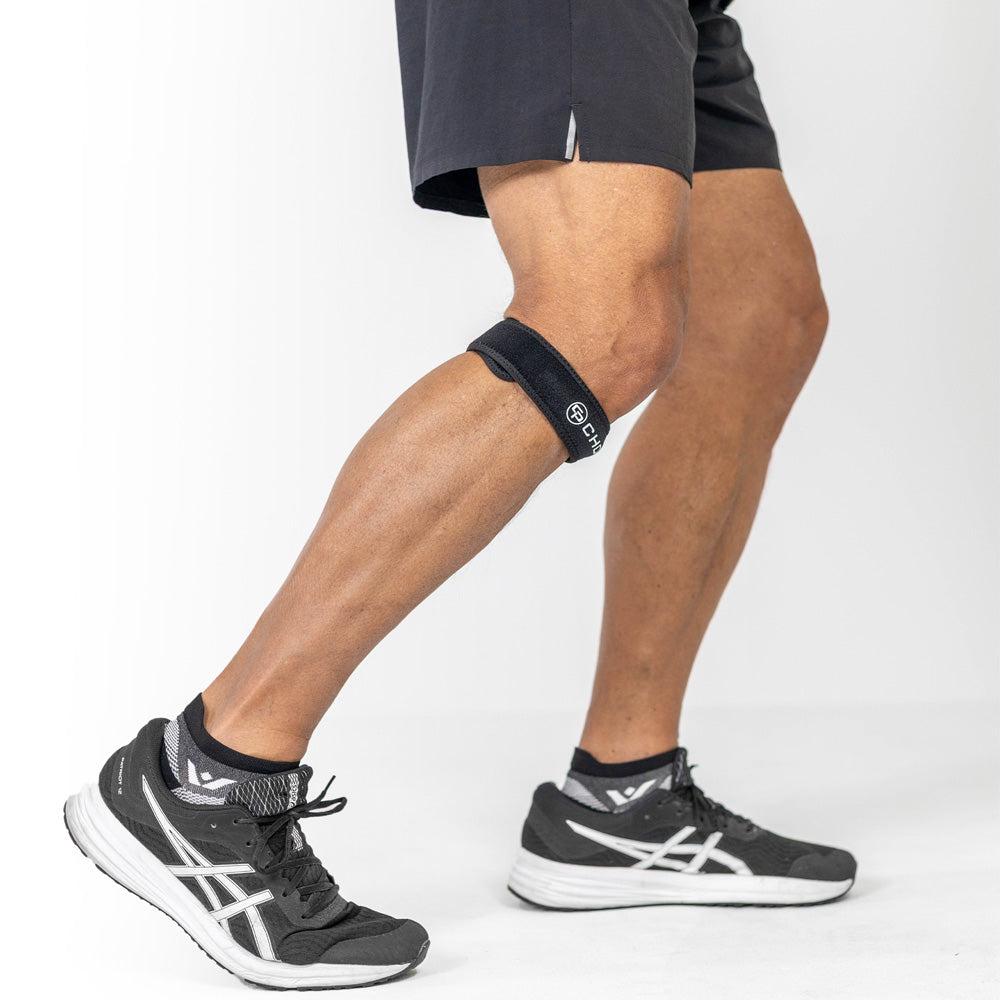 Person walking indoors wearing the Cho-Pat Patella Knee Strap positioned below the kneecap.