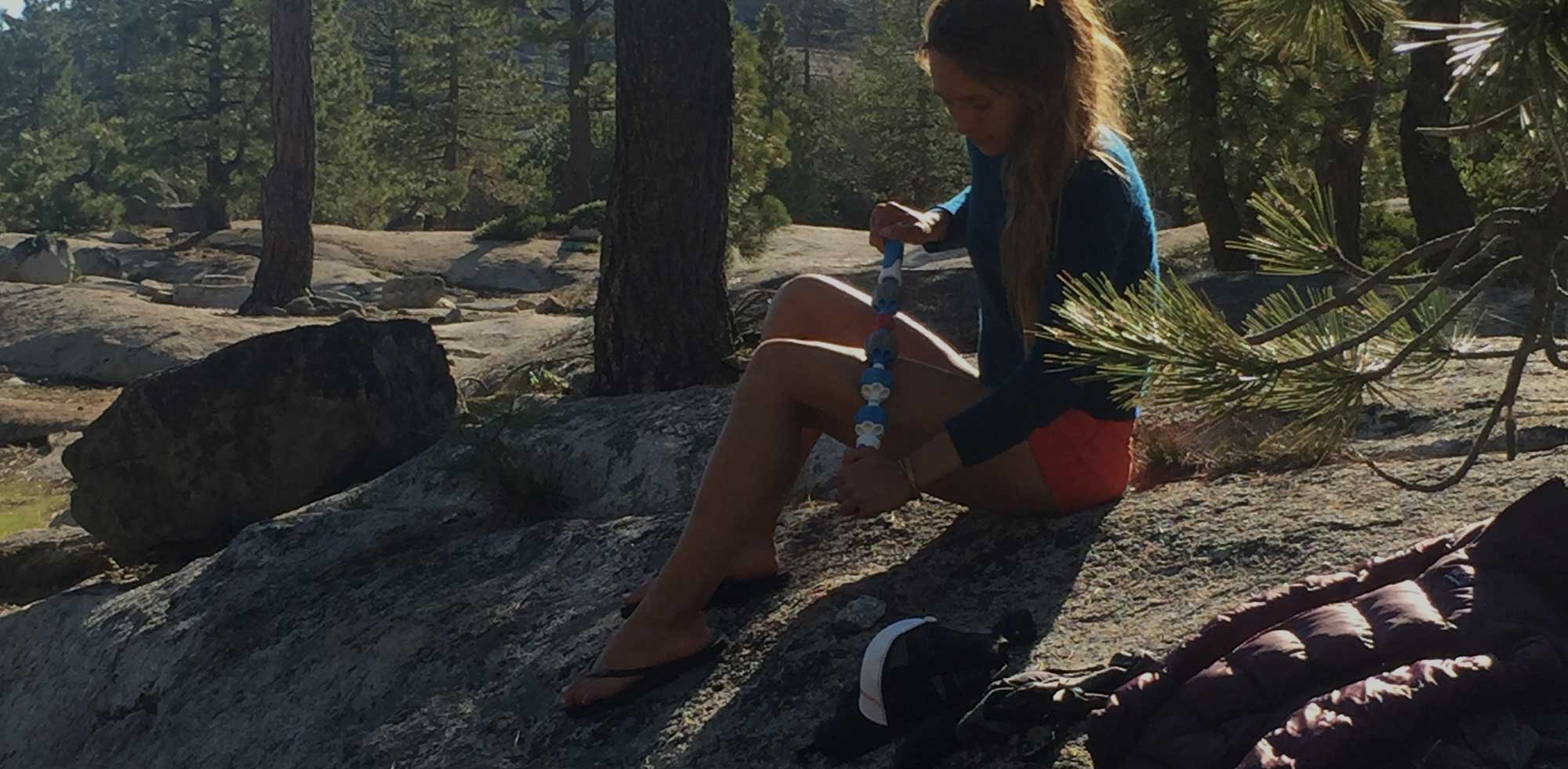 lady maasaging leg with pro roller in the forest