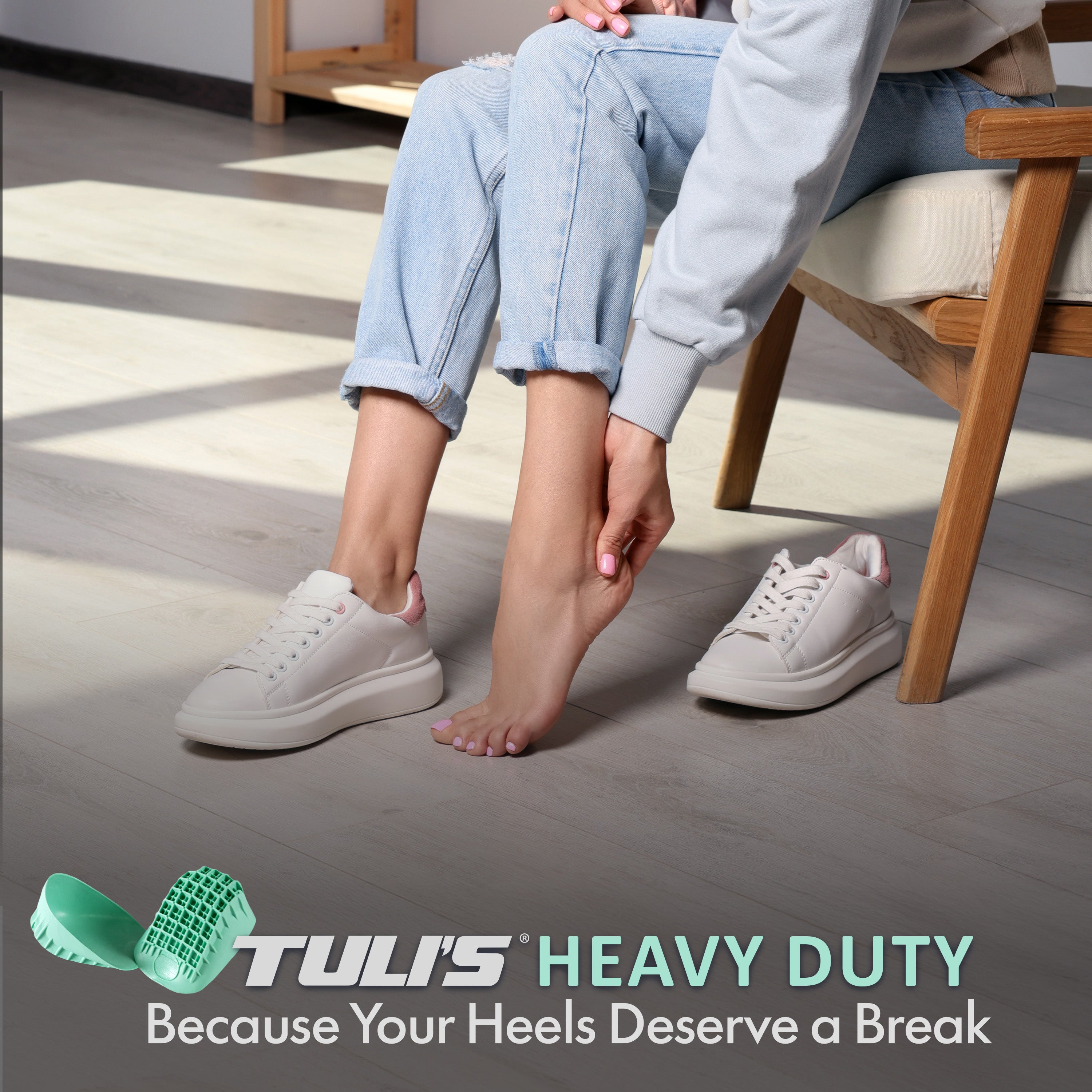 Person seated indoors holding heel area with Tuli’s Heavy Duty Heel Cups product displayed.
